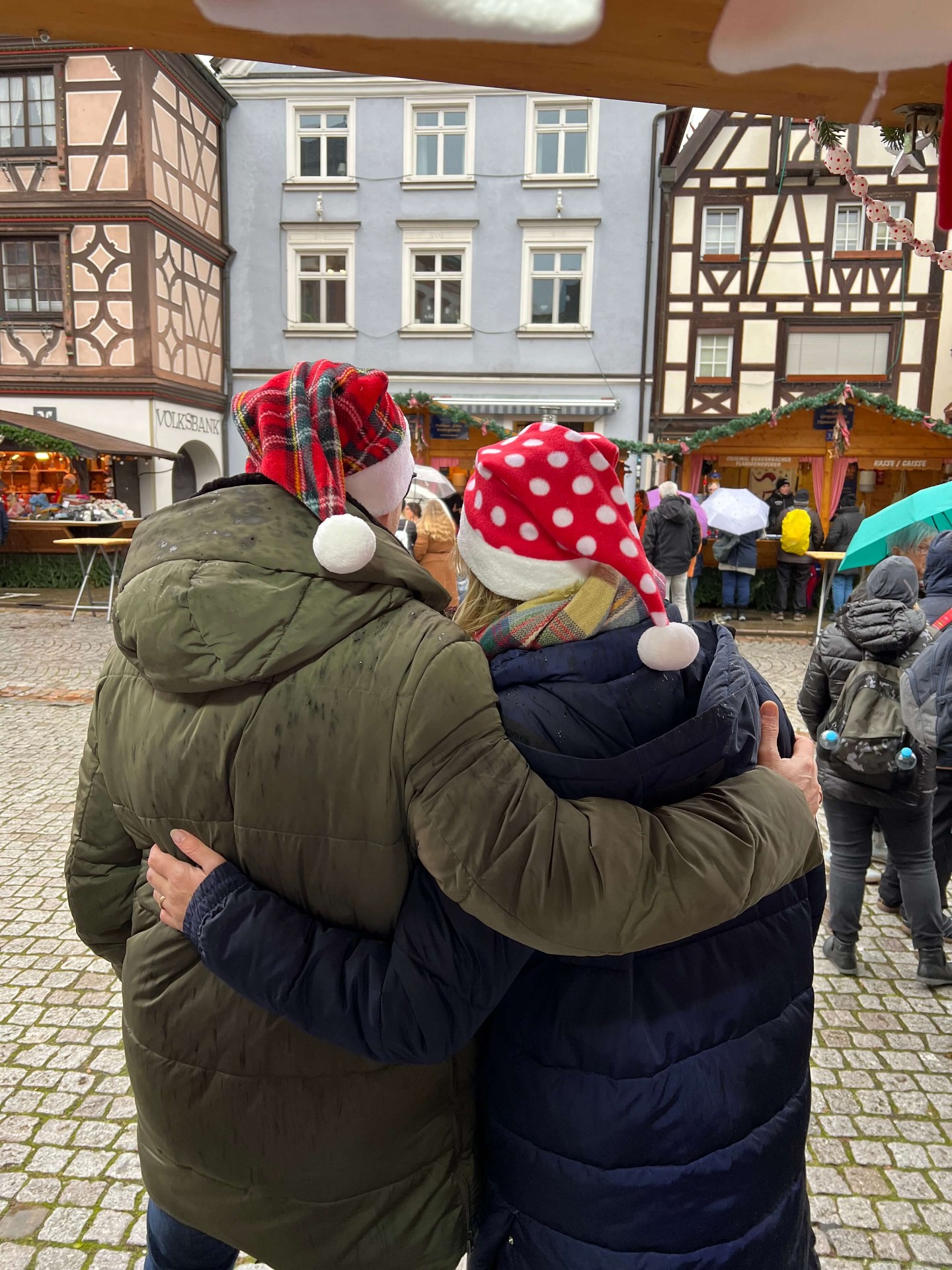 Paar mit Weihnachtsmützen vor Fachwerkhäusern