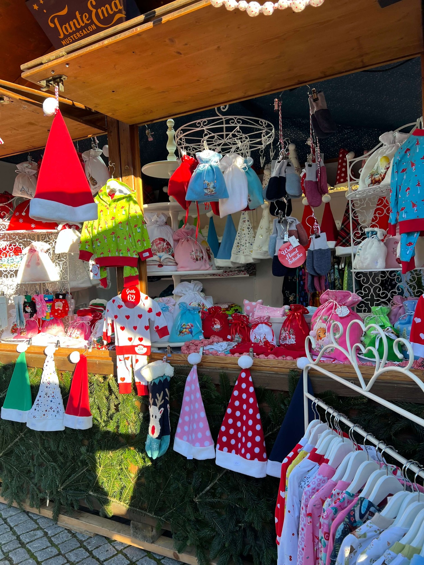 Sortiment mit Mützen und Kinderkleidung im Sonnenlicht