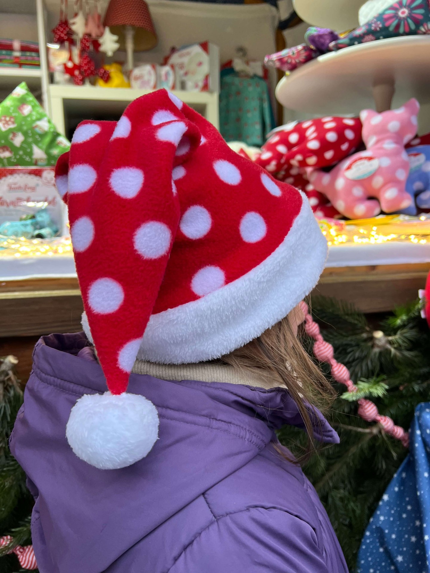 Kind mit roter Punkte-Weihnachtsmütze vor dem Stand